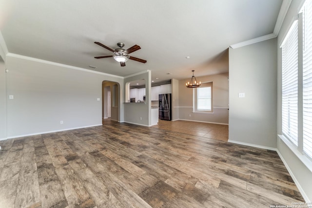 26215 Presidio Blf, Boerne, TX 78015 - unfurnished living room with ceiling fan, a chandelier, dark wood-style flooring, crown molding, and arched walkways