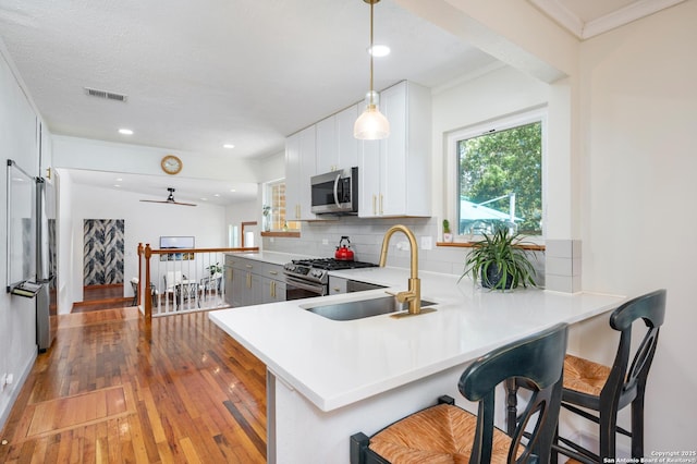 227 Devonshire, San Antonio, TX 78209 - kitchen with stainless steel appliances, light wood-style floors, backsplash, a peninsula, and a kitchen breakfast bar