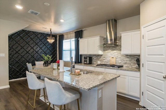 12904 Liam Ct, Saint Hedwig, TX 78152 - kitchen with wall chimney range hood, stainless steel gas cooktop, a chandelier, white cabinetry, and dark wood-type flooring