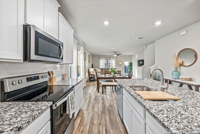 3016 Muscat, Schertz, TX 78154 - kitchen featuring appliances with stainless steel finishes, light wood-style floors, white cabinetry, light stone counters, and recessed lighting