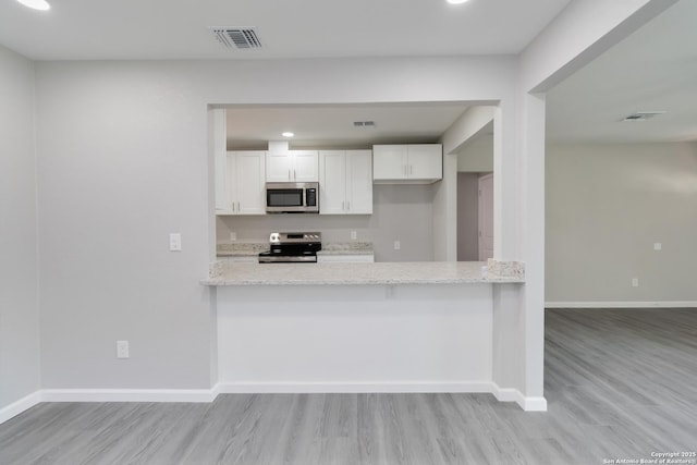 2738 Ravina, San Antonio, TX 78222 - kitchen with stainless steel appliances, light wood-style floors, white cabinets, a peninsula, and recessed lighting