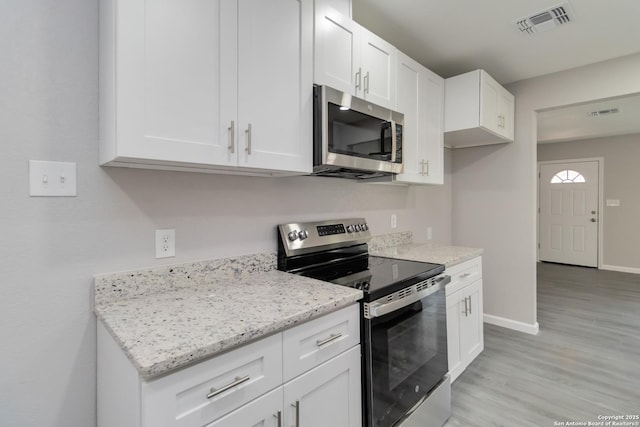 2738 Ravina, San Antonio, TX 78222 - kitchen featuring appliances with stainless steel finishes, white cabinetry, light wood-style flooring, and light stone countertops