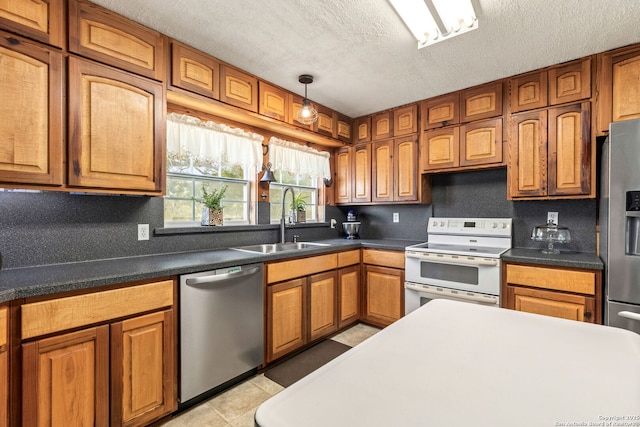 2 Fm 289, Comfort, TX 78013 - kitchen featuring stainless steel appliances, a textured ceiling, brown cabinetry, dark countertops, and light tile patterned floors