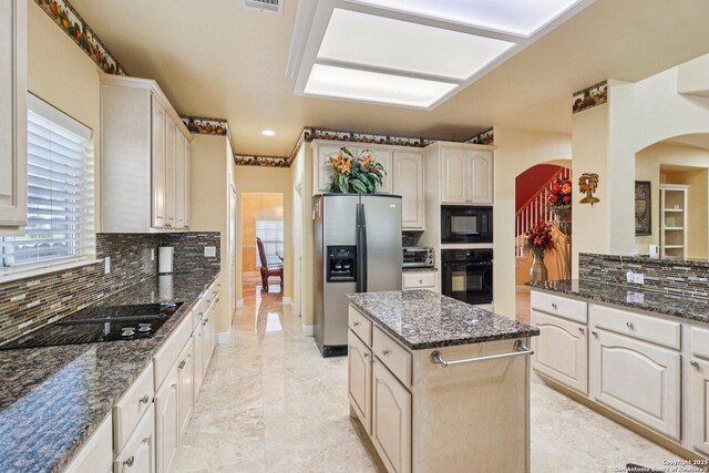 1810 Three Frks, San Antonio, TX 78258 - kitchen featuring black appliances, arched walkways, backsplash, a kitchen island, and dark stone countertops
