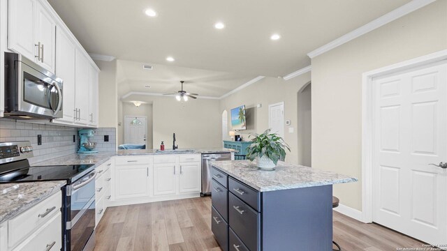 21810 Thunder Basin, San Antonio, TX 78261 - kitchen with stainless steel appliances, ornamental molding, light wood-type flooring, white cabinetry, and arched walkways