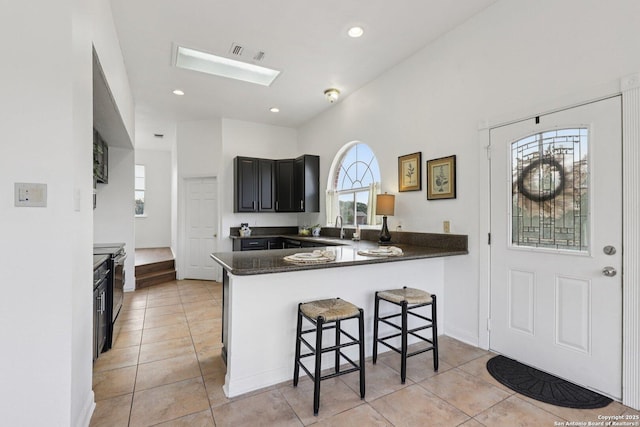 23613 Grayling Ln, San Antonio, TX 78259 - kitchen featuring light tile patterned floors, electric stove, a breakfast bar, dark countertops, and recessed lighting