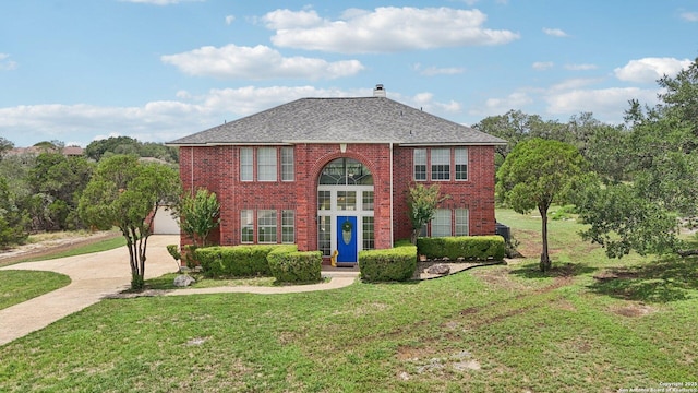 23613 Grayling Ln, San Antonio, TX 78259 - view of front of house featuring brick siding, a front lawn, a chimney, driveway, and roof with shingles