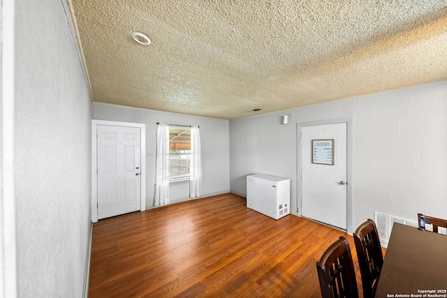 702 John Adams, San Antonio, TX 78228 - unfurnished living room with a textured ceiling, wood finished floors, and a textured wall