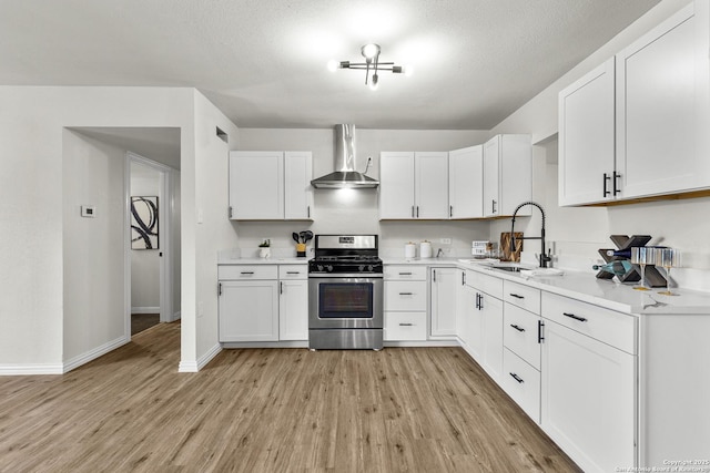 4426 Newcome, San Antonio, TX 78229 - kitchen with stainless steel range with gas cooktop, wall chimney exhaust hood, light wood-type flooring, and white cabinetry