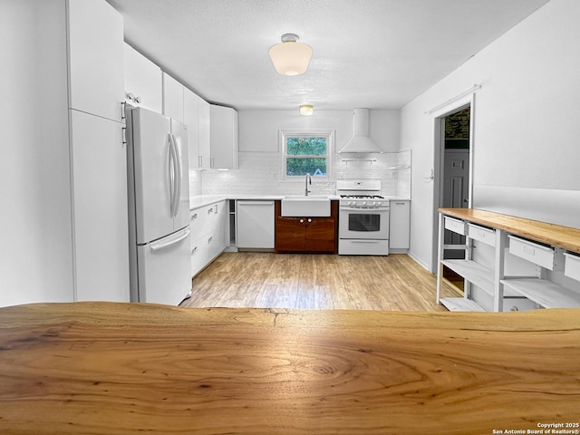 737 N Central, New Braunfels, TX 78130 - kitchen with white appliances, wall chimney exhaust hood, tasteful backsplash, light wood-type flooring, and white cabinets