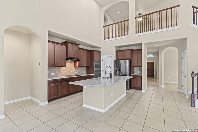 8503 Kallison Arbor, San Antonio, TX 78254 - kitchen with appliances with stainless steel finishes, decorative backsplash, light tile patterned floors, a towering ceiling, and a kitchen island with sink