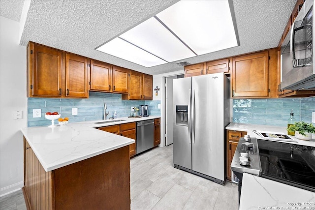 3527 Oakhorne St, San Antonio, TX 78247 - kitchen featuring stainless steel appliances, brown cabinets, a textured ceiling, a peninsula, and backsplash