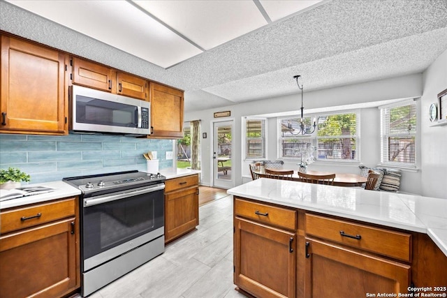 3527 Oakhorne St, San Antonio, TX 78247 - kitchen featuring stainless steel appliances, light countertops, brown cabinetry, a chandelier, and a textured ceiling