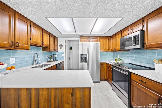 3527 Oakhorne St, San Antonio, TX 78247 - kitchen with appliances with stainless steel finishes, brown cabinets, a peninsula, decorative backsplash, and a textured ceiling