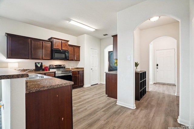 6123 Foster Ml, San Antonio, TX 78222 - kitchen with black microwave, stainless steel range with electric stovetop, light wood-style floors, arched walkways, and dark brown cabinets