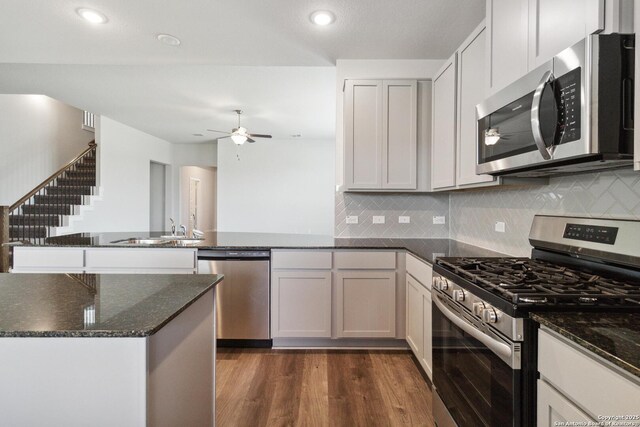1619 Vista View Dr, Pleasanton, TX 78064 - kitchen featuring appliances with stainless steel finishes, a peninsula, dark stone countertops, dark wood finished floors, and backsplash