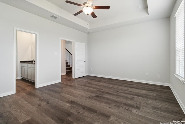 1619 Vista View Dr, Pleasanton, TX 78064 - unfurnished bedroom featuring a tray ceiling, dark wood-type flooring, ensuite bathroom, and a ceiling fan