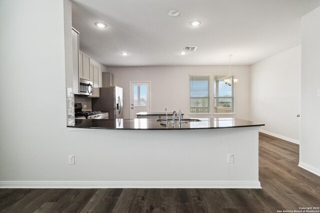 1619 Vista View Dr, Pleasanton, TX 78064 - kitchen featuring stainless steel appliances, dark countertops, a chandelier, dark wood finished floors, and a peninsula