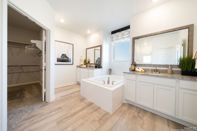 1562 Vista View Dr, Pleasanton, TX 78064 - bathroom featuring vanity, a bath, wood finished floors, and a walk in closet