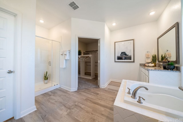 1562 Vista View Dr, Pleasanton, TX 78064 - bathroom featuring a shower stall, wood finished floors, a bath, a spacious closet, and vanity