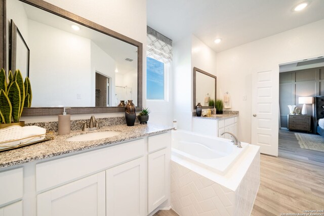 1562 Vista View Dr, Pleasanton, TX 78064 - ensuite bathroom with vanity, a bath, wood finished floors, and recessed lighting