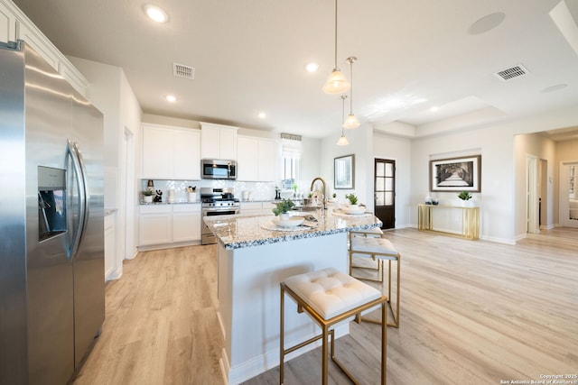 1562 Vista View Dr, Pleasanton, TX 78064 - kitchen featuring stainless steel appliances, light wood-style flooring, light stone countertops, recessed lighting, and white cabinetry