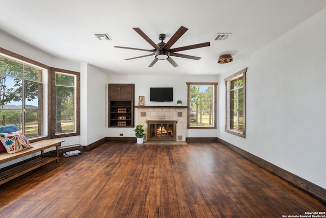 13132 State Highway 16, Medina, TX 78055 - unfurnished living room featuring a ceiling fan, dark wood-type flooring, a fireplace, and plenty of natural light