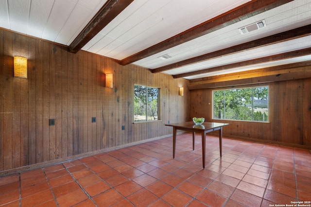 13132 State Highway 16, Medina, TX 78055 - unfurnished dining area with beam ceiling, wood walls, and tile patterned floors
