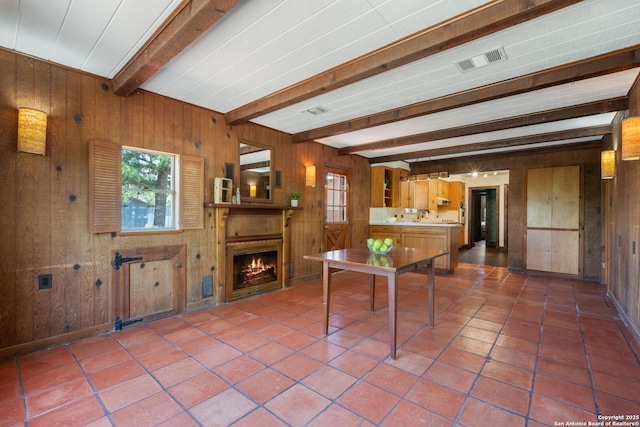 13132 State Highway 16, Medina, TX 78055 - kitchen with wooden walls, beam ceiling, a lit fireplace, plenty of natural light, and brown cabinets