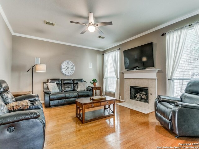 2115 Encino Breeze, San Antonio, TX 78259 - living area featuring ceiling fan, a tile fireplace, light wood-style floors, and crown molding