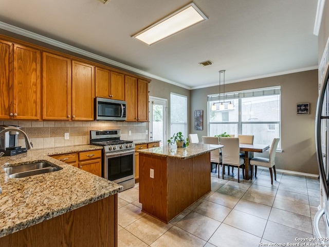 2115 Encino Breeze, San Antonio, TX 78259 - kitchen featuring appliances with stainless steel finishes, brown cabinets, decorative backsplash, a center island, and crown molding