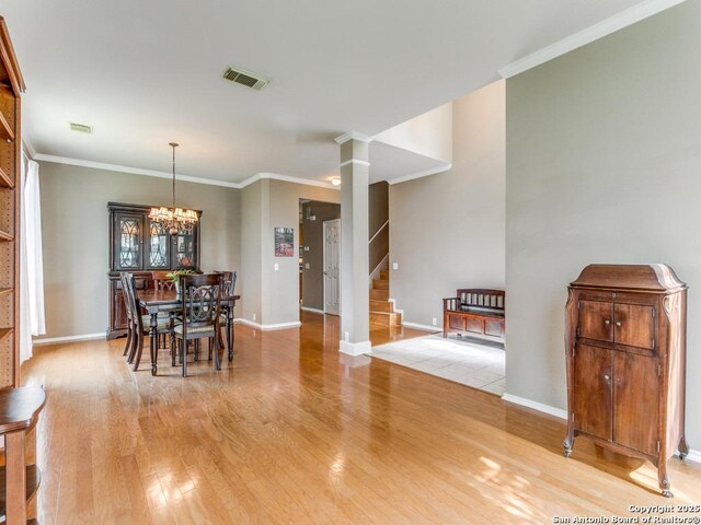2115 Encino Breeze, San Antonio, TX 78259 - dining room with light wood-style floors, stairway, a chandelier, crown molding, and ornate columns