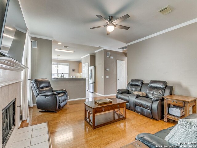 2115 Encino Breeze, San Antonio, TX 78259 - living room featuring ornamental molding, light wood finished floors, a tile fireplace, and ceiling fan