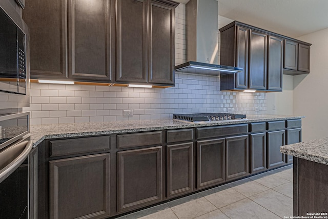 12455 Diagon Aly, San Antonio, TX 78254 - kitchen with wall chimney range hood, stainless steel appliances, dark brown cabinetry, backsplash, and light tile patterned floors