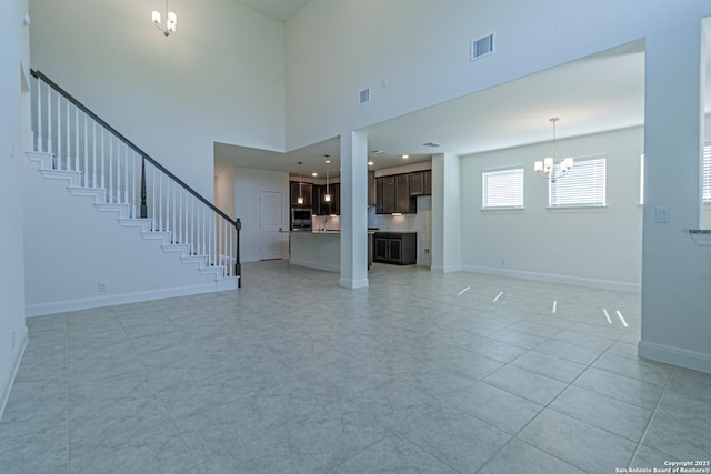 12455 Diagon Aly, San Antonio, TX 78254 - unfurnished living room featuring a chandelier, stairs, light tile patterned flooring, and a towering ceiling