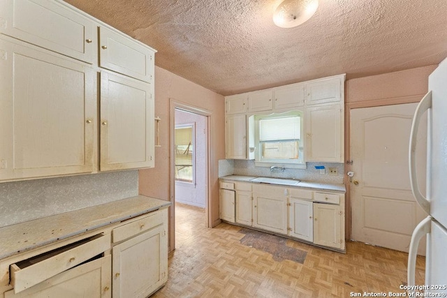518 Wright Ave, Schertz, TX 78154 - kitchen featuring freestanding refrigerator, light countertops, a textured ceiling, backsplash, and white cabinetry