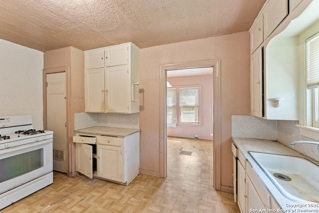 518 Wright Ave, Schertz, TX 78154 - kitchen with white range with gas cooktop, light countertops, white cabinets, and a textured ceiling