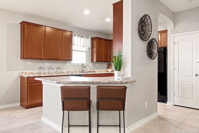 2059 Wind Chime, New Braunfels, TX 78130 - kitchen with a kitchen breakfast bar, brown cabinets, a peninsula, light tile patterned flooring, and recessed lighting