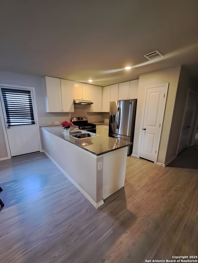 318 Pradera Cv, San Antonio, TX 78237 - kitchen featuring stainless steel appliances, wood finished floors, a peninsula, white cabinetry, and dark stone counters