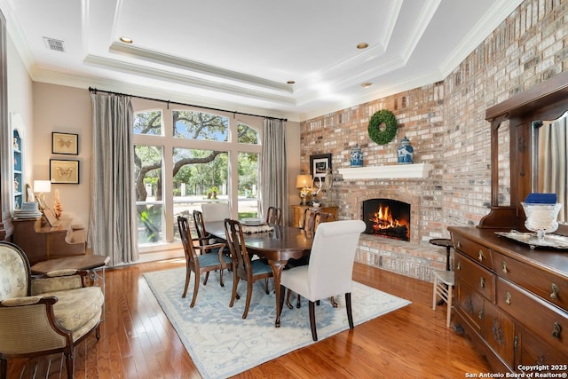 5 Remington, San Antonio, TX 78258 - dining room featuring a raised ceiling, a brick fireplace, wood finished floors, and crown molding
