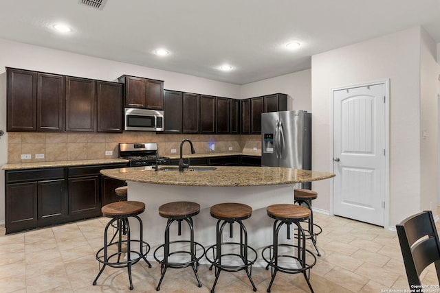 15102 Field Sparrow, San Antonio, TX 78253 - kitchen with appliances with stainless steel finishes, a kitchen bar, tasteful backsplash, light stone counters, and a center island with sink