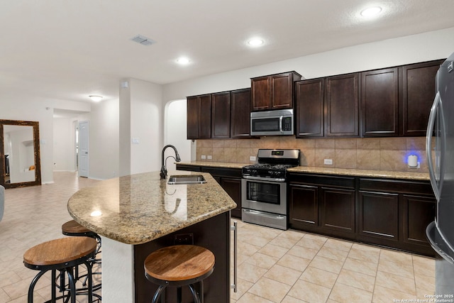 15102 Field Sparrow, San Antonio, TX 78253 - kitchen with stainless steel appliances, a breakfast bar area, backsplash, light stone countertops, and a center island with sink