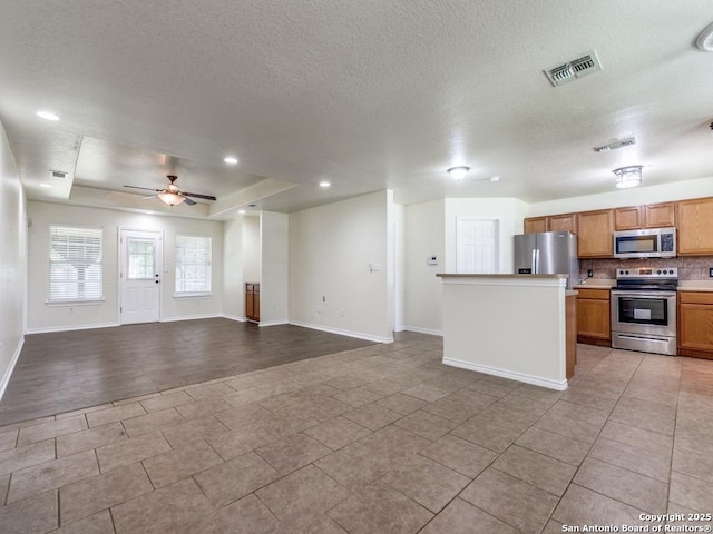 97 Windcrest, Floresville, TX 78114 - unfurnished living room featuring a textured ceiling, ceiling fan, light tile patterned flooring, recessed lighting, and a tray ceiling