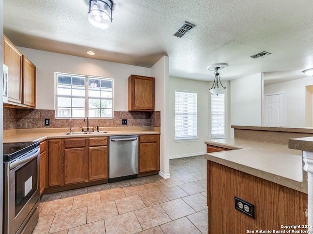 97 Windcrest, Floresville, TX 78114 - kitchen featuring stainless steel appliances, brown cabinetry, decorative backsplash, light countertops, and a textured ceiling
