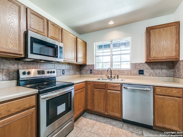 97 Windcrest, Floresville, TX 78114 - kitchen with stainless steel appliances, light countertops, brown cabinetry, and tasteful backsplash