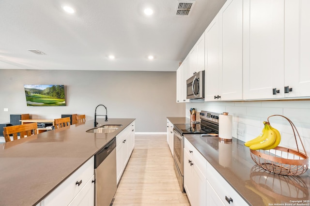 13215 Turnesa Ter, San Antonio, TX 78221 - kitchen with appliances with stainless steel finishes, recessed lighting, light wood finished floors, decorative backsplash, and white cabinetry