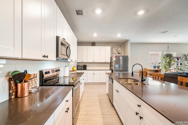 13215 Turnesa Ter, San Antonio, TX 78221 - kitchen with appliances with stainless steel finishes, light wood-style floors, tasteful backsplash, recessed lighting, and white cabinets