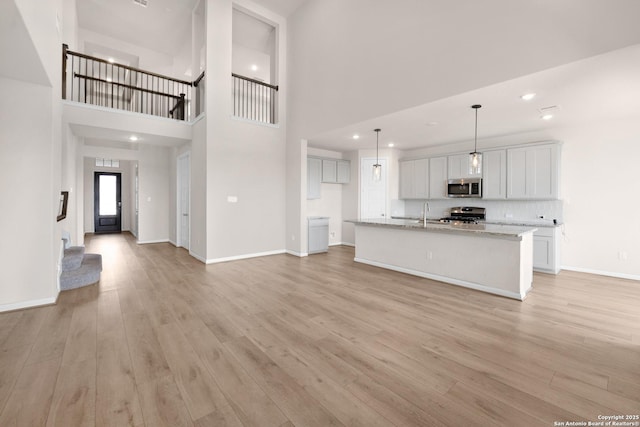 2614 Banditos Rdg, San Antonio, TX 78245 - unfurnished living room featuring light wood-style flooring, a towering ceiling, and recessed lighting