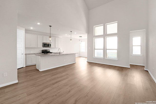 2614 Banditos Rdg, San Antonio, TX 78245 - unfurnished living room featuring light wood-style floors, plenty of natural light, recessed lighting, and a towering ceiling