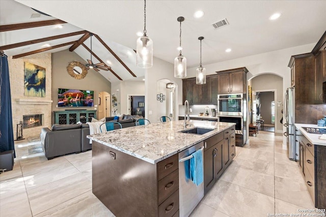26815 Duet Dr, San Antonio, TX 78260 - kitchen with stainless steel appliances, arched walkways, dark brown cabinetry, recessed lighting, and an island with sink